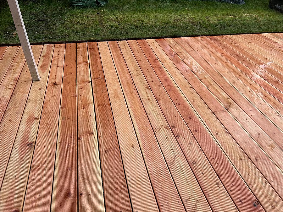 Frisch verlegte Terrassendielen aus Lärche, am Rand der Rasen